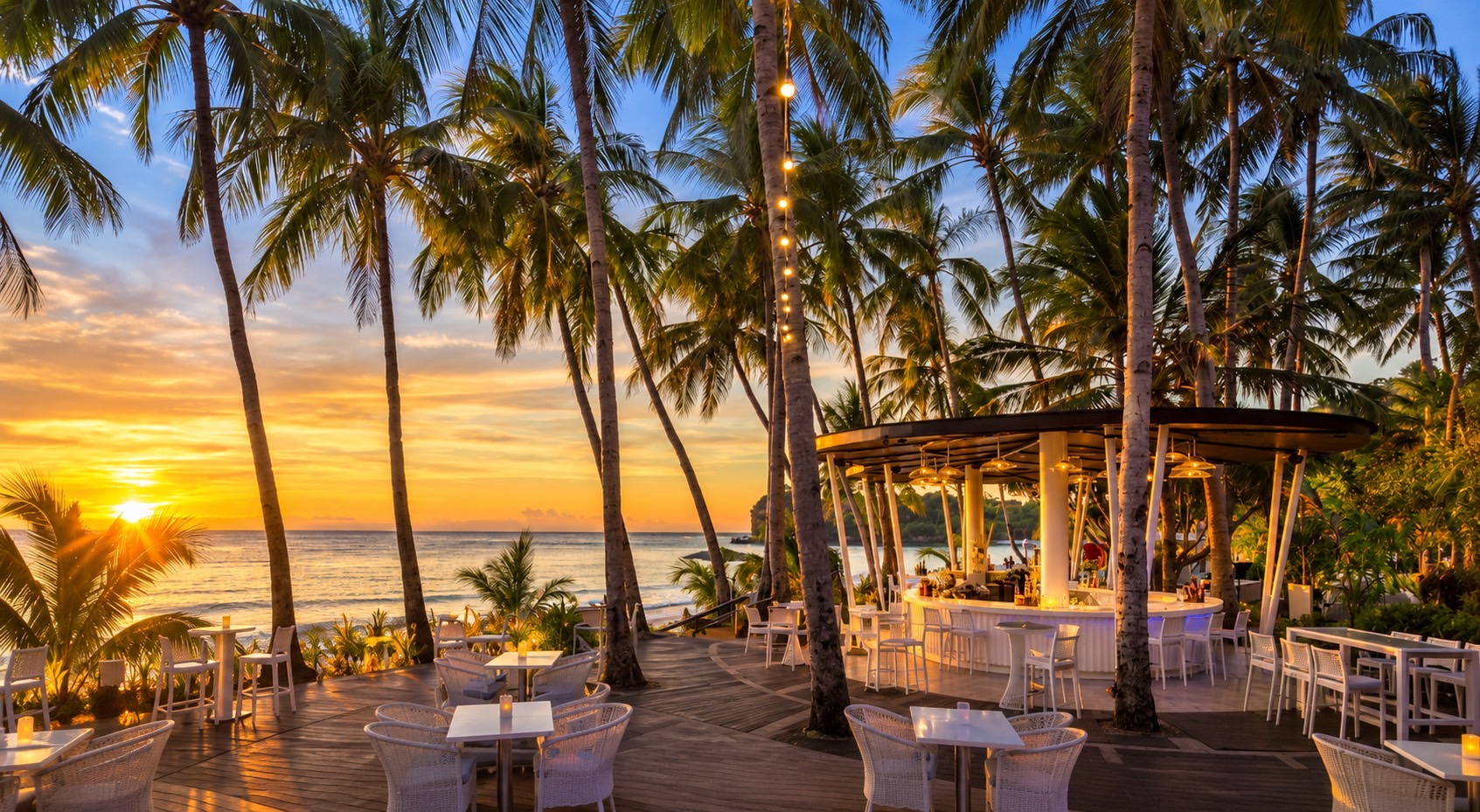 A beach bar under palms at sunset